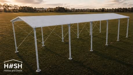 Open-sided galvanised steel farm shelter on grassland at sunset